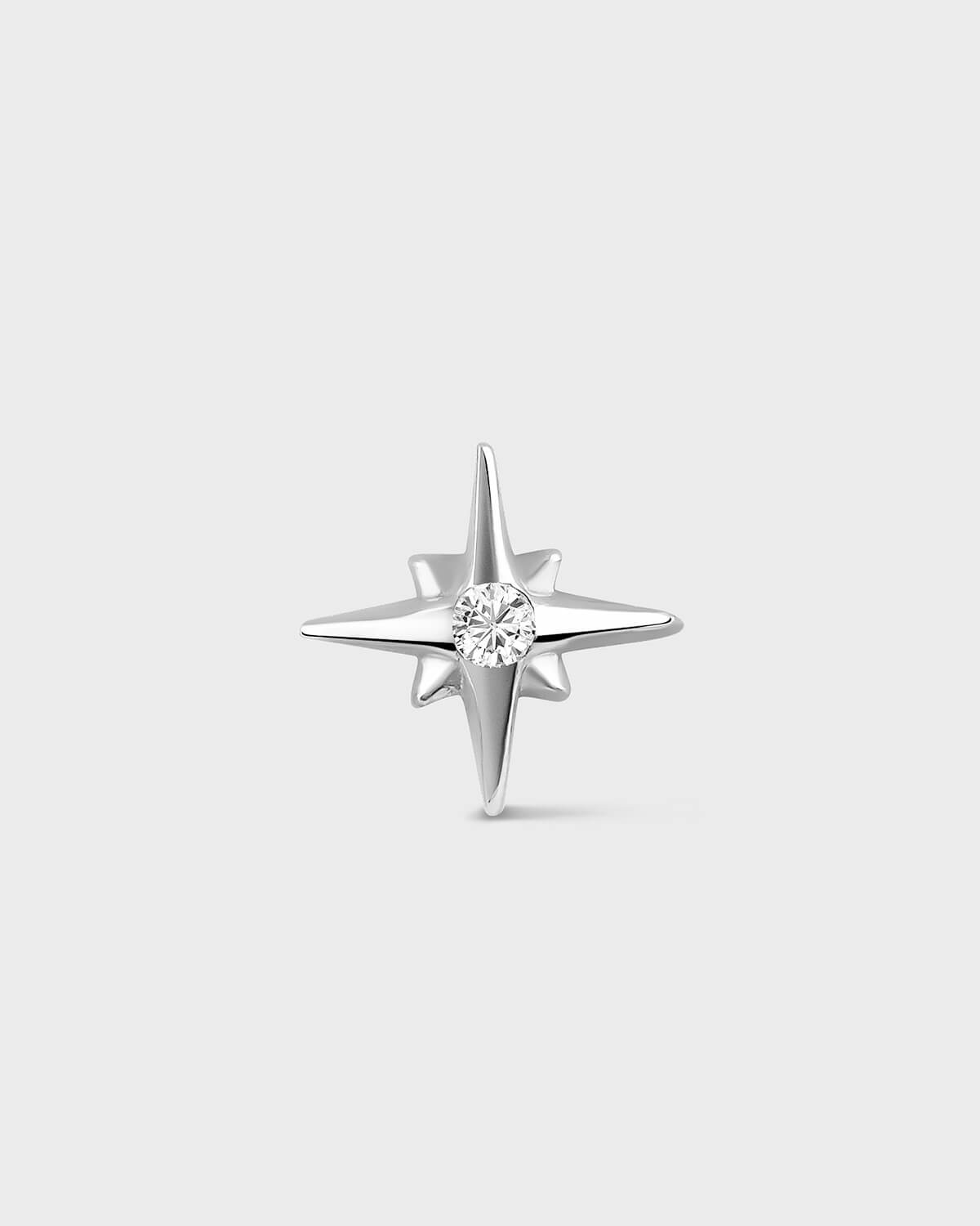 White gold star shape earring with central clear gemstone on a light gray backround