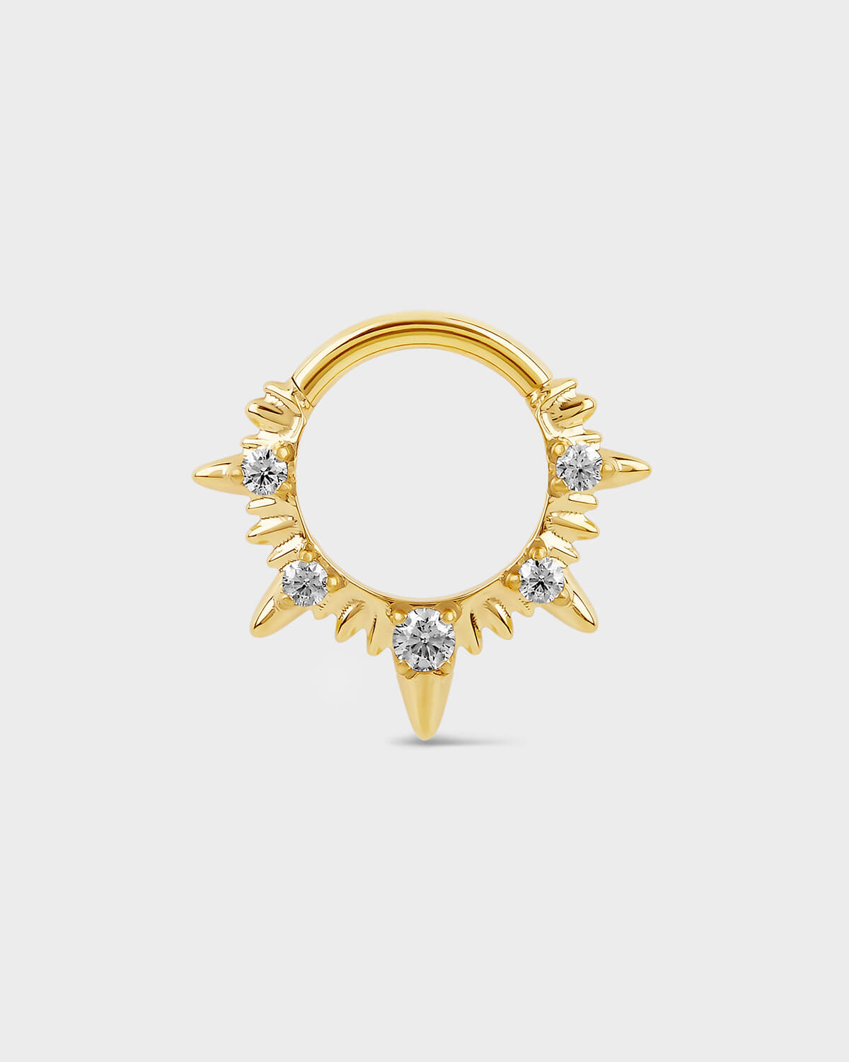Gold septum ring with diamond-like stones on a light gray background