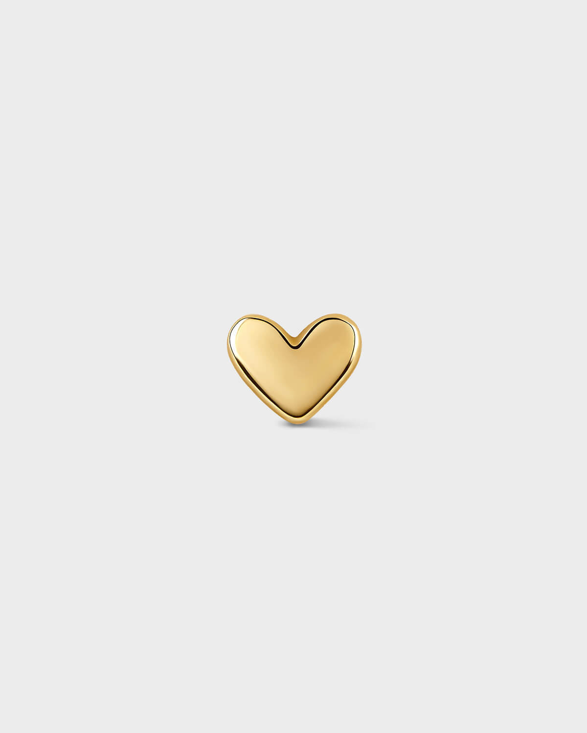 Gold heart-shaped earring on a light gray background