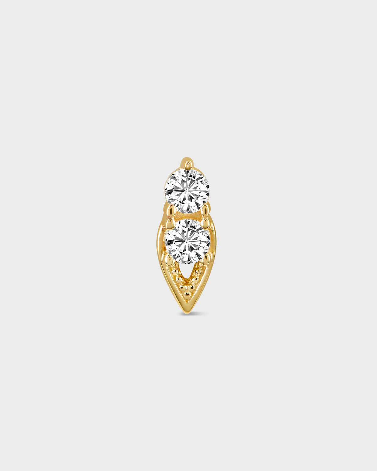 Gold earring with two clear gemstones on a light gray background