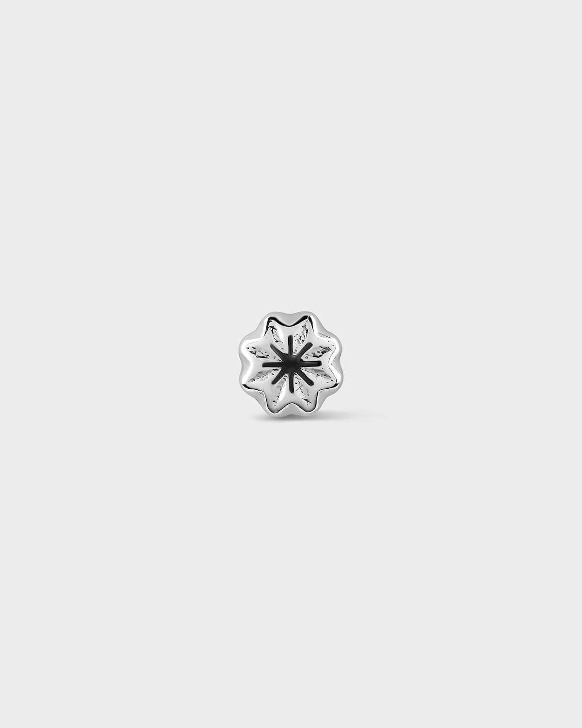 Silver charm with a black center on a light gray background