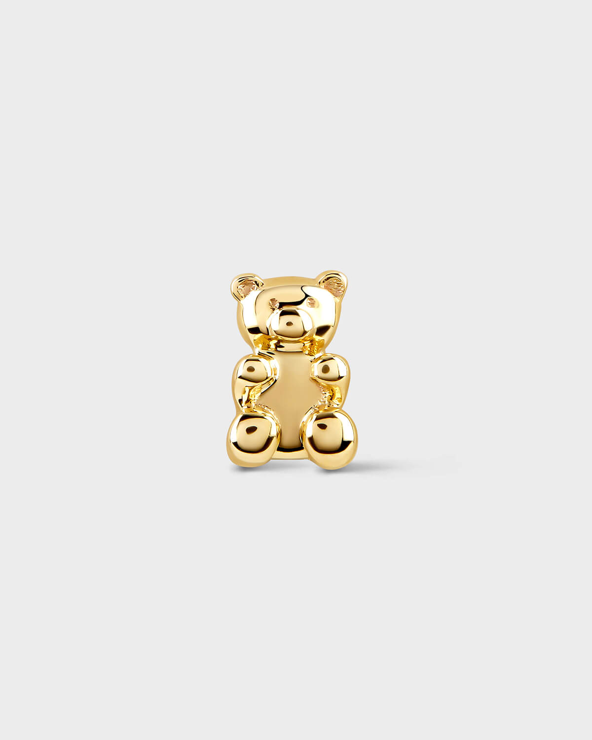 Gold teddy bear earring on a light gray background