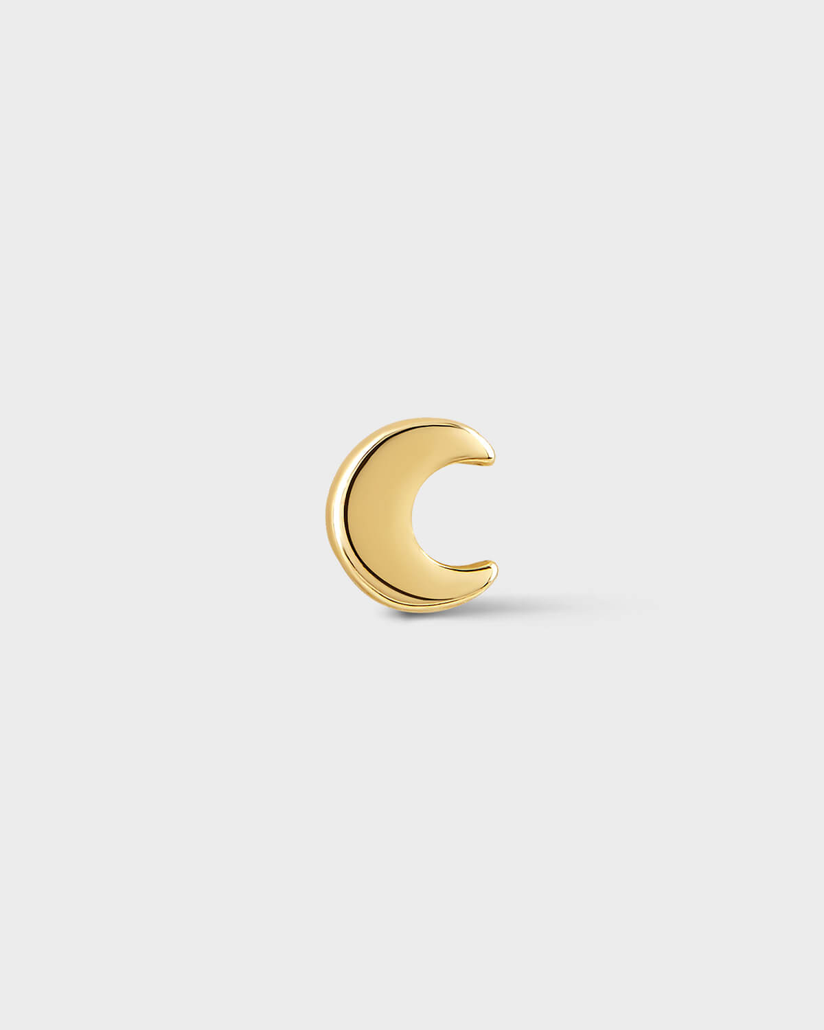Gold crescent moon earring on a light gray background