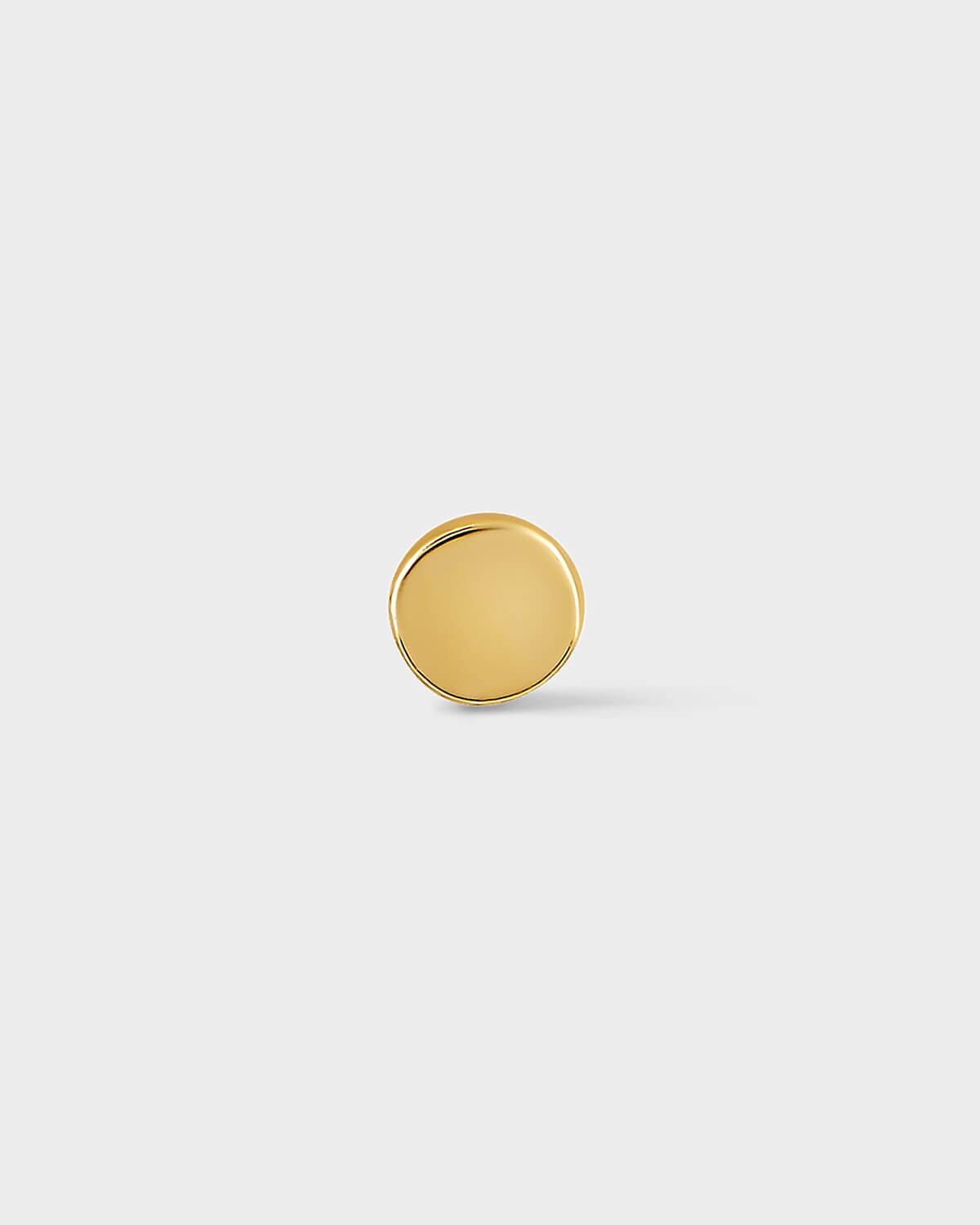 Gold round earring on a light gray background