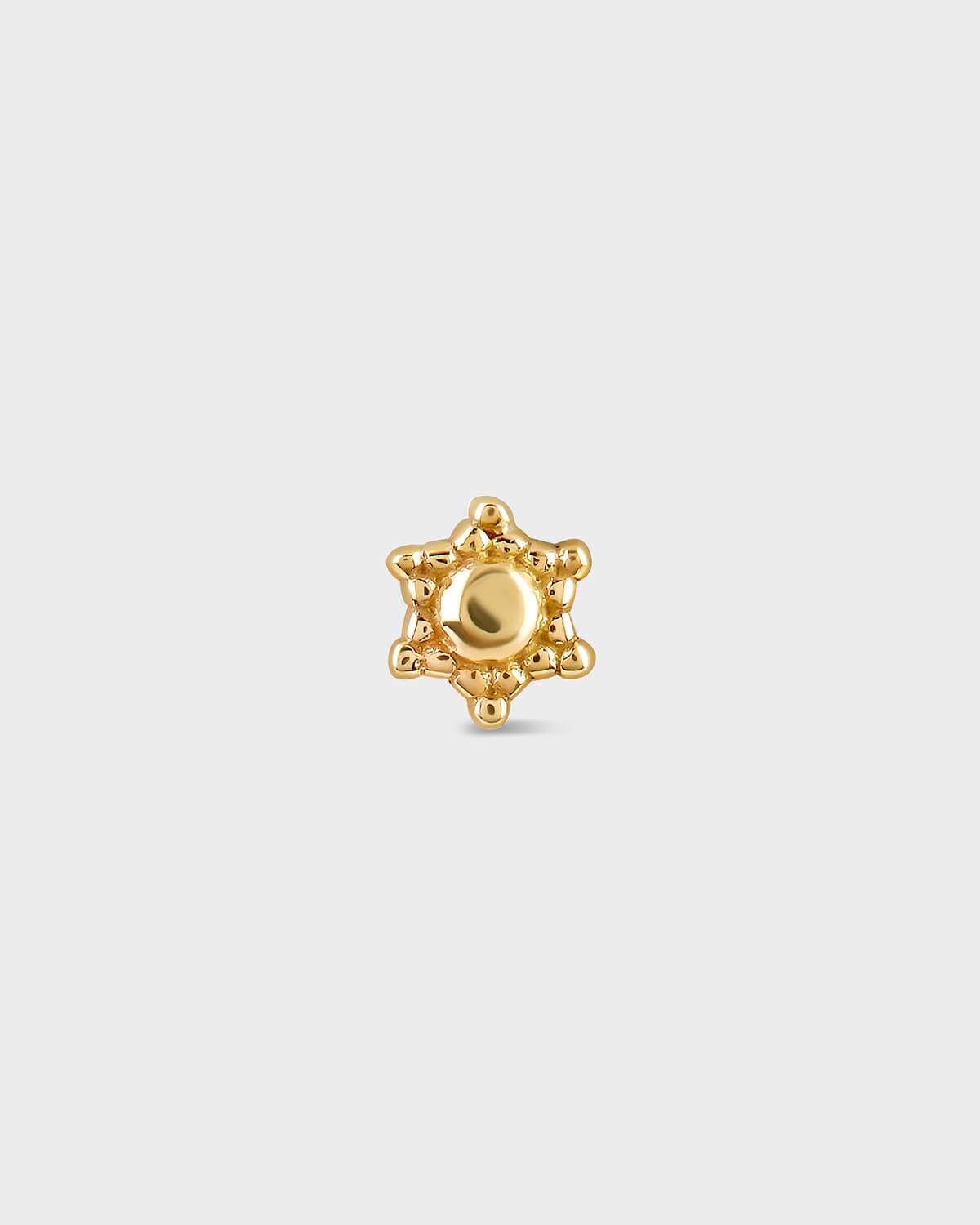 Gold star-shaped earring on a light gray background