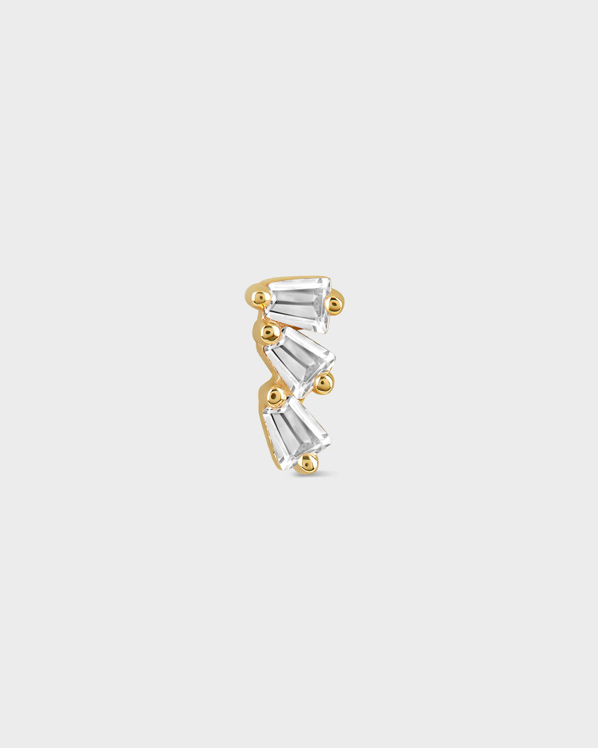 Gold earring on a light gray background