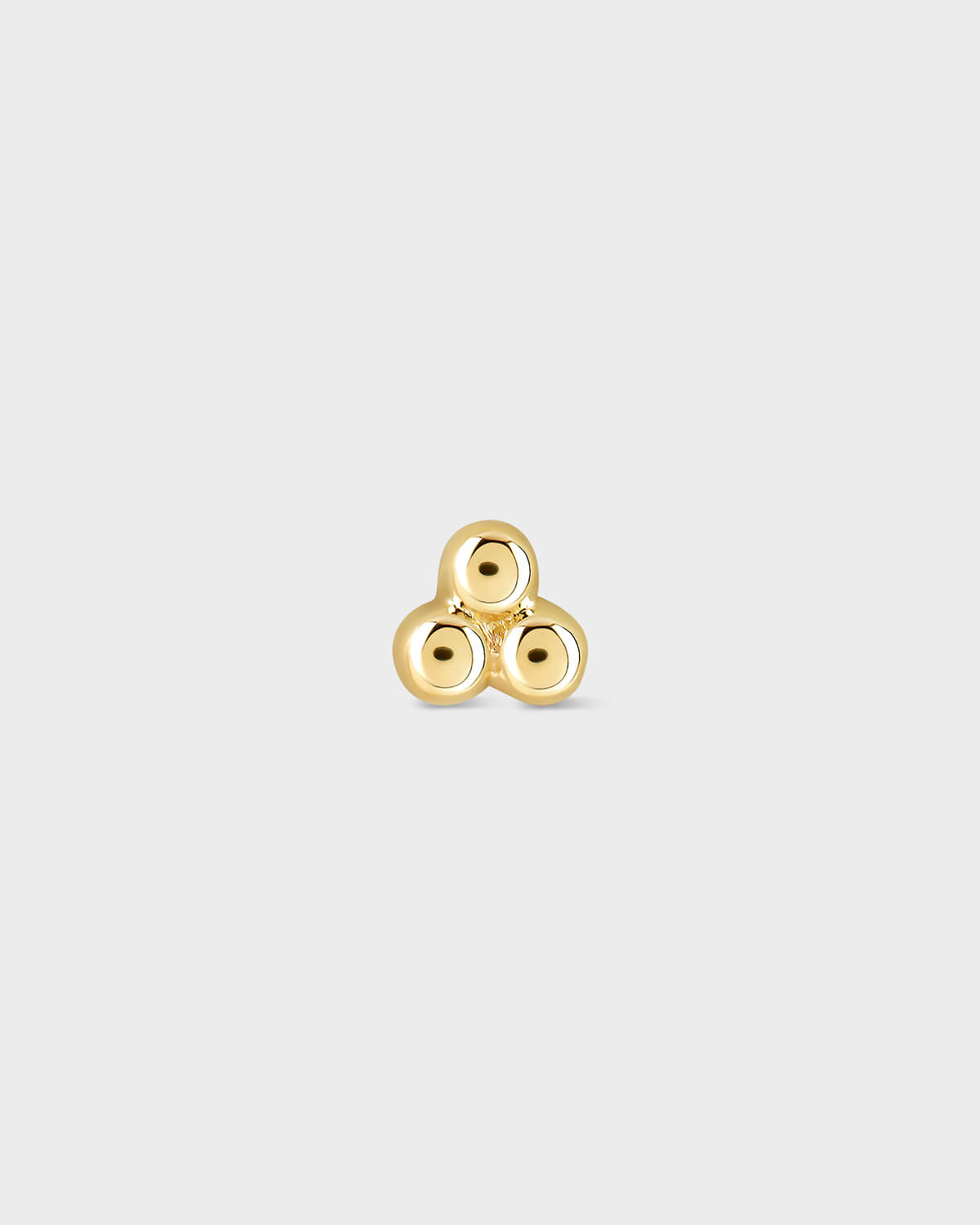 Gold triskele earring on a light gray background