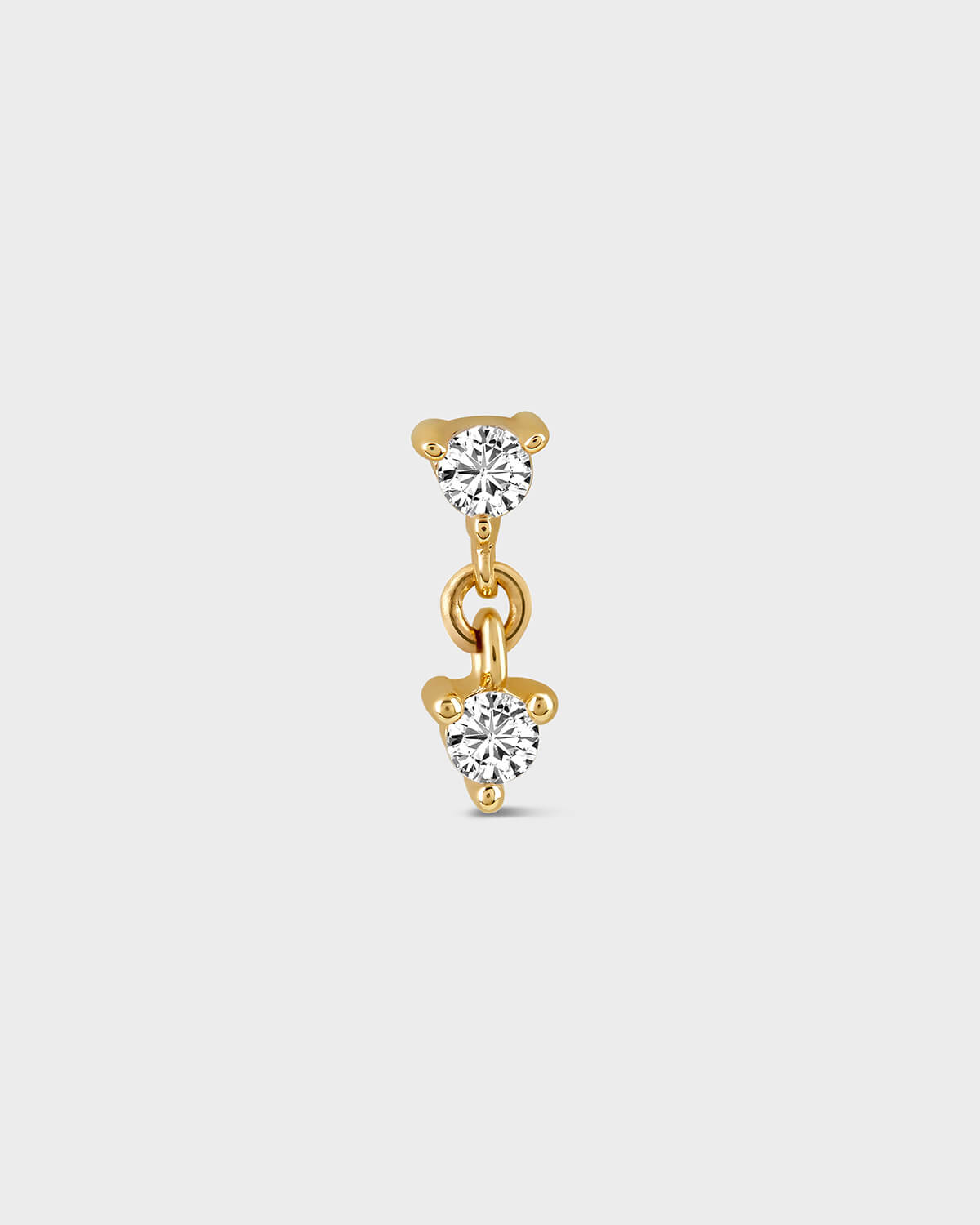 Gold earring with two clear gemstones on a light gray background