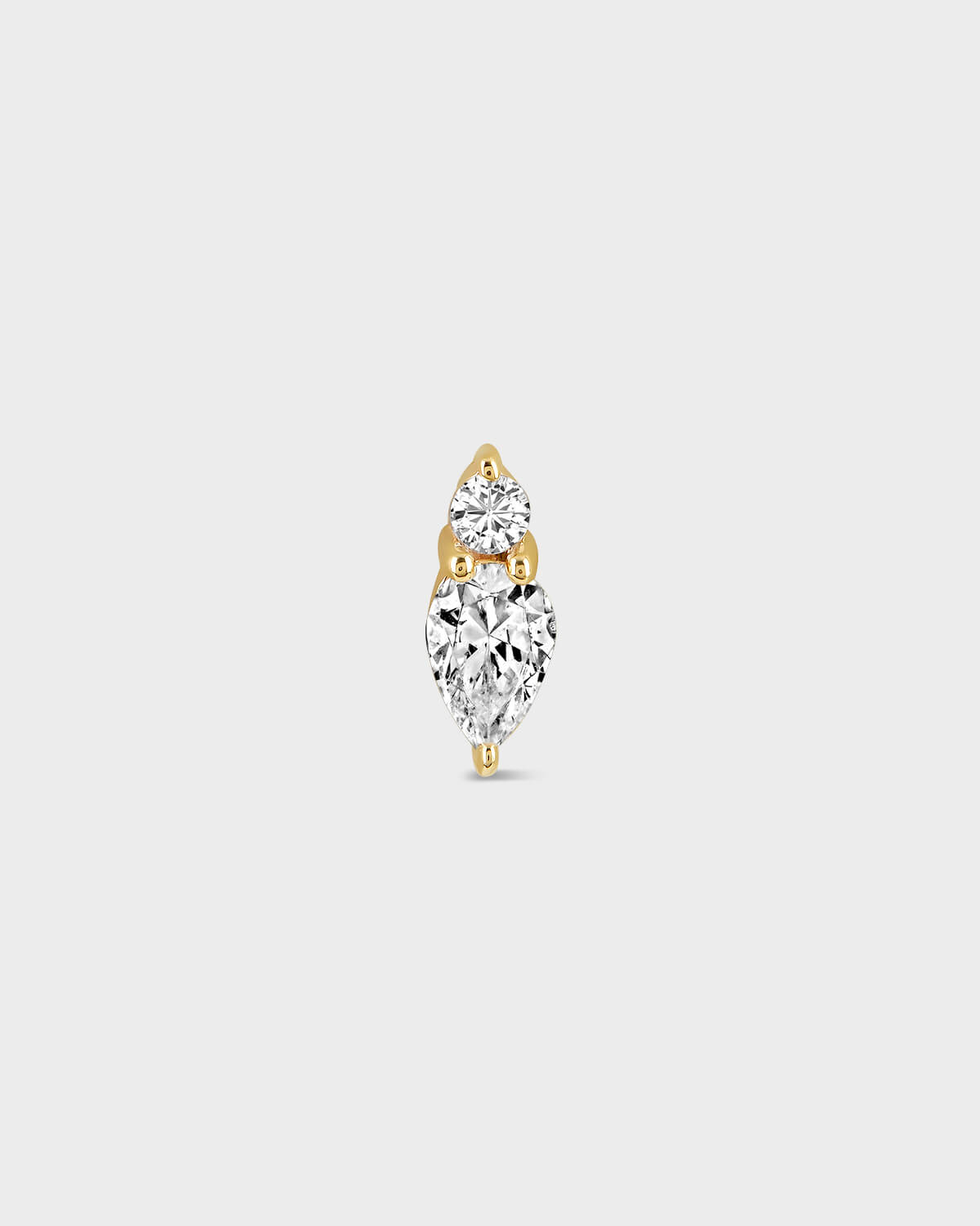 Gold and diamond earring on a light gray background