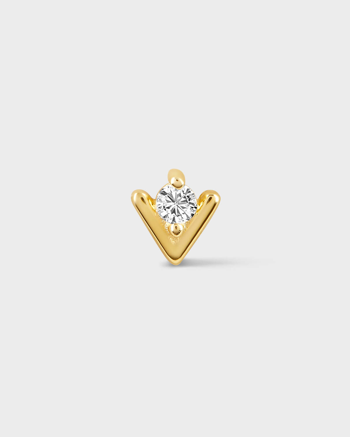 Gold earring with a diamond on a light gray background