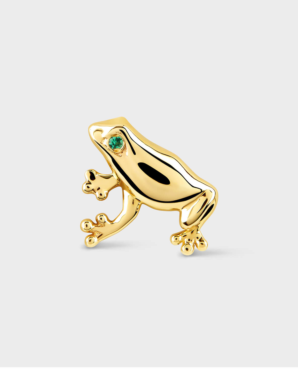 Gold frog-shaped earring with a green gemstone on a light gray background